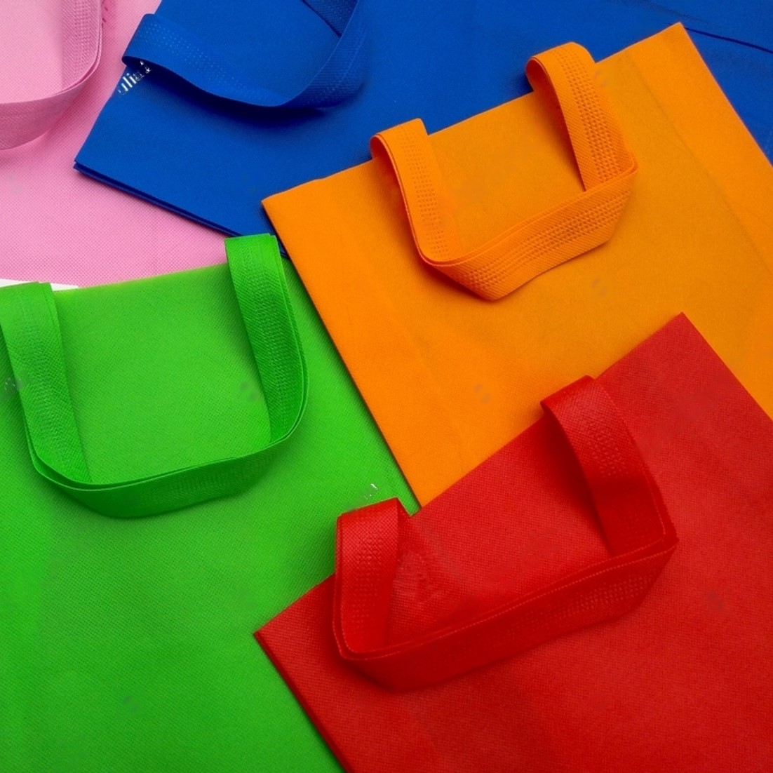 stock-photo-pink-green-orange-white-and-blue-polypropylene-bags-pile-of-tote-bags-of-non-woven-fabric-with-2165686485-transformed